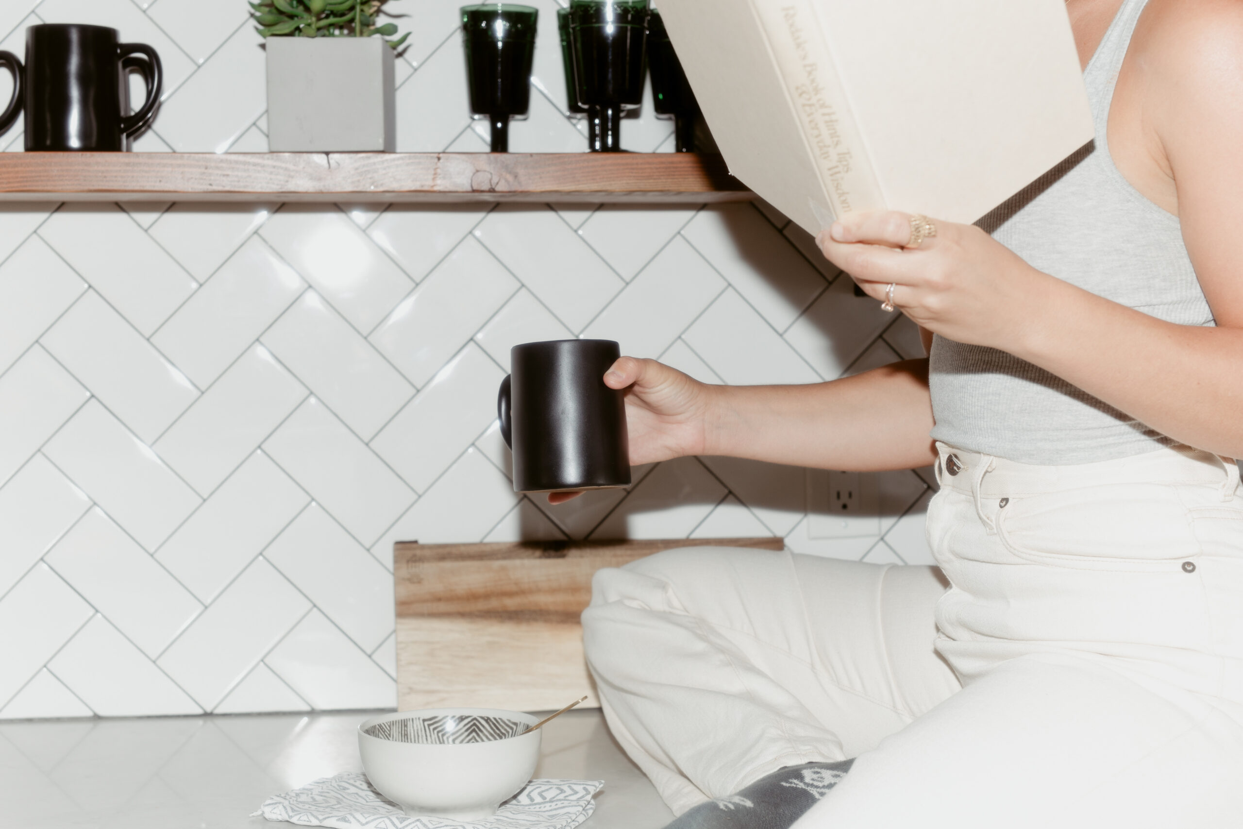 A copywriter reads a book about copywriting vs. content writer while drinking coffee on the kitchen counter.