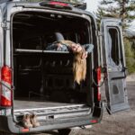 A copywriter hangs out of the back of her converted van.